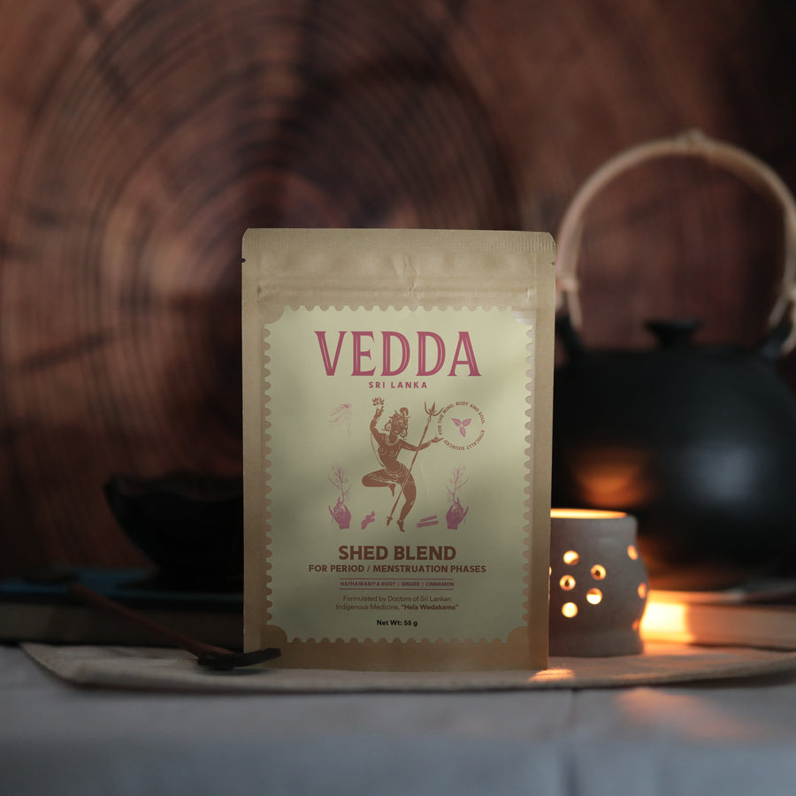 A stand-up pouch of VEDDA by SINGAPORE Shed Blend herbal tea, set against a warm, rustic background with a teapot and candlelight.